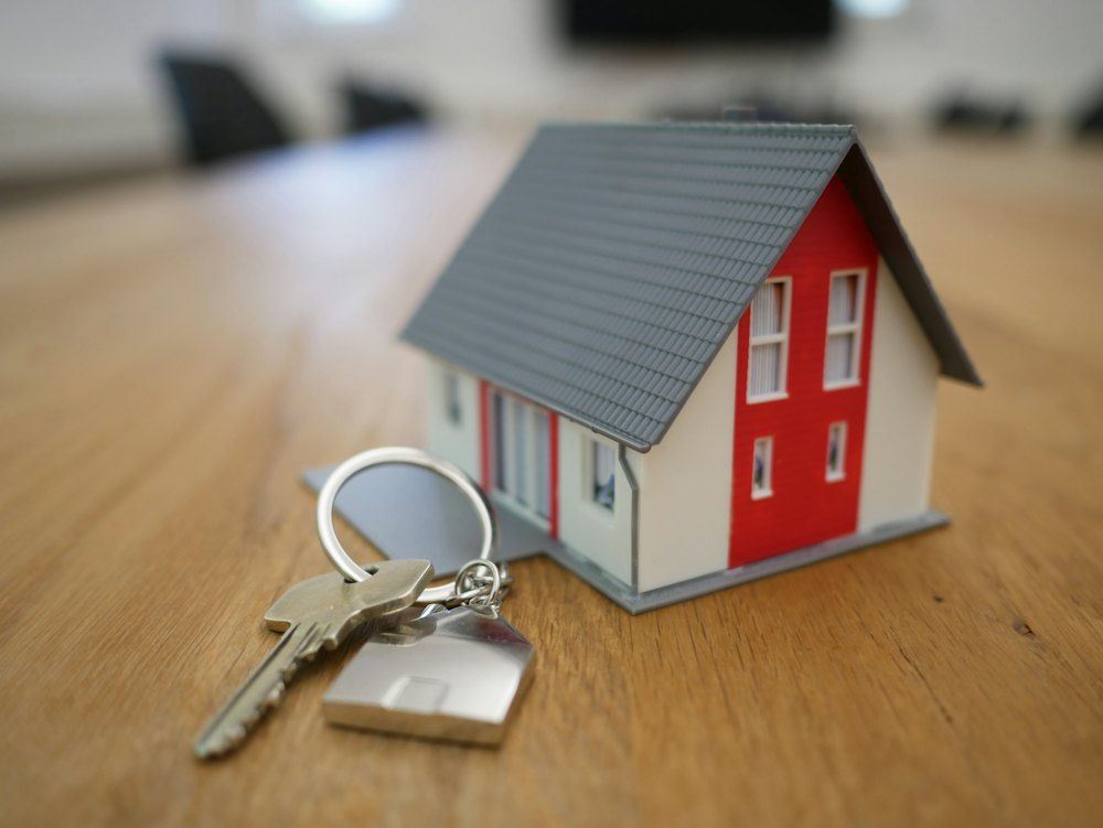 Un juego de llaves y una casita de maqueta sobre una mesa de madera