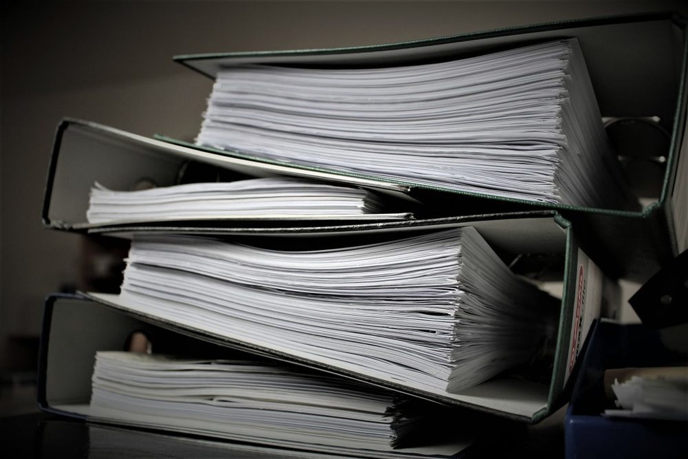 Pila de carpetas y biblioratos con documentación acumulada