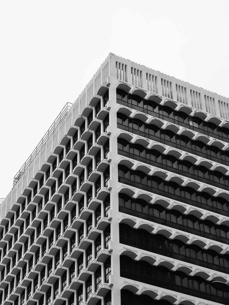 Esquina de un edificio moderno con balcones curvos repetidos, contrapicado en blanco y negro